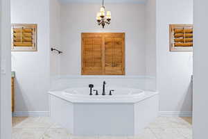 Bathroom featuring a notable chandelier, a bathtub, and tile patterned flooring