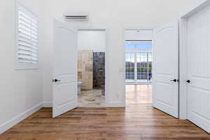 Interior space featuring wood-type flooring, ensuite bath, and a wall mounted air conditioner