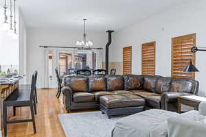 Living room with a notable chandelier, a wood stove, light hardwood / wood-style floors, and plenty of natural light