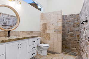 Bathroom with tile walls, vanity, toilet, and a shower