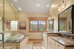 Bathroom with tiled tub, vanity, and vaulted ceiling