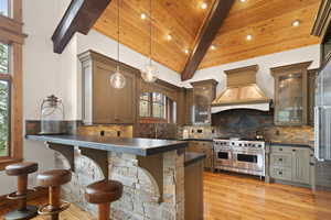 Kitchen with pendant lighting, range with two ovens, a breakfast bar, and wood ceiling