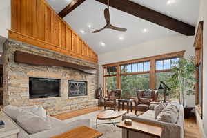 Living room featuring high vaulted ceiling, light wood-type flooring, beam ceiling, and ceiling fan