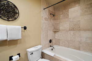 Bathroom with tiled shower / bath combo and toilet