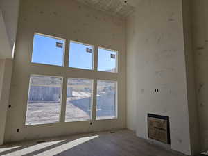 Unfurnished living room featuring a high ceiling, plenty of natural light, and heating unit