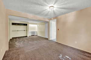 Interior space featuring a textured ceiling and carpet flooring