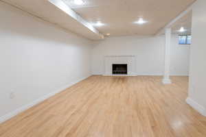 Unfurnished living room with light hardwood / wood-style flooring, a drop ceiling, and a fireplace