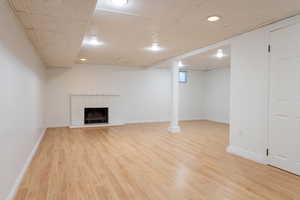 Unfurnished living room featuring a brick fireplace, light hardwood / wood-style flooring, and a drop ceiling