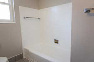 Bathroom featuring toilet, shower / bathing tub combination, and tile patterned floors