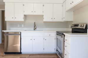 Kitchen featuring white cabinetry, sink, light hardwood / wood-style flooring, and stainless steel appliances