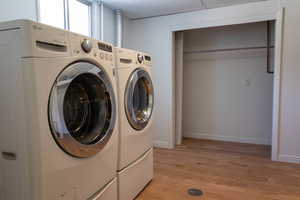 Washroom featuring light hardwood / wood-style floors and washing machine and clothes dryer