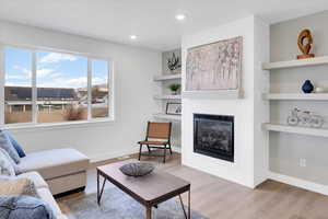 Living room featuring built in shelves, hardwood / wood-style floors, and a fireplace