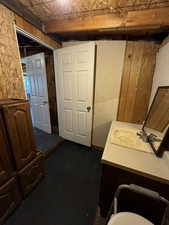 Interior space with beamed ceiling, vanity, and wooden walls