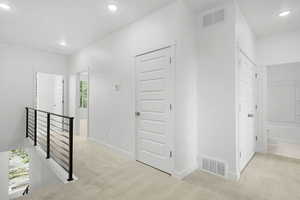 Hallway featuring light colored carpet