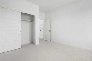 Unfurnished bedroom with light colored carpet and a closet