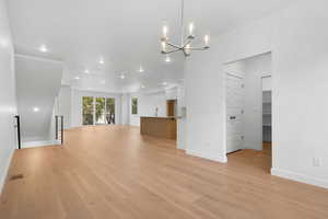 Unfurnished living room featuring light wood-type flooring, an inviting chandelier, and sink