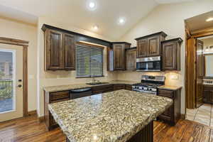 Kitchen with dark hardwood / wood-style floors, sink, vaulted ceiling, a kitchen island, and stainless steel appliances