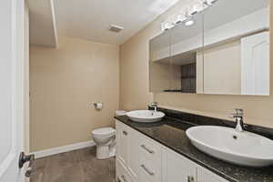 Bathroom featuring vanity, tile patterned flooring, toilet, and a textured ceiling