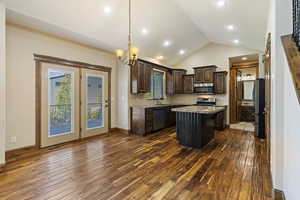 Kitchen featuring lofted ceiling, dark wood-type flooring, appliances with stainless steel finishes, and a kitchen island