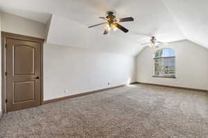 Additional living space with vaulted ceiling, ceiling fan, and carpet flooring