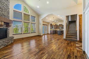 Unfurnished living room featuring high vaulted ceiling, a chandelier, a fireplace, and dark hardwood / wood-style flooring