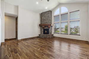 Unfurnished living room featuring high vaulted ceiling, ceiling fan, hardwood / wood-style flooring, and a fireplace