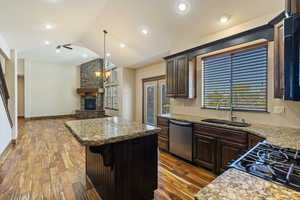 Kitchen with vaulted ceiling, stainless steel appliances, wood-type flooring, a center island, and sink