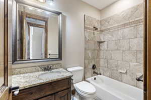 Full bathroom featuring tiled shower / bath, vanity, and toilet