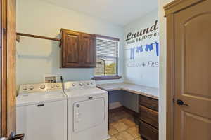 Clothes washing area featuring cabinets, light tile patterned floors, and washer and dryer