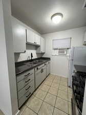 Kitchen featuring gas stove, a textured ceiling, sink, white cabinetry, and light tile patterned floors