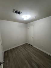 Empty room featuring a textured ceiling and dark wood-type flooring