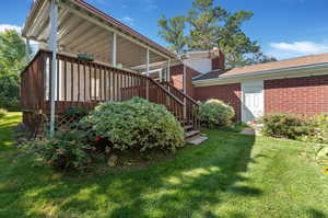 View of side of home featuring a lawn and a deck