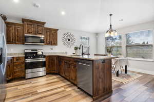 Kitchen with appliances with stainless steel finishes, light hardwood / wood-style floors, sink, and plenty of natural light