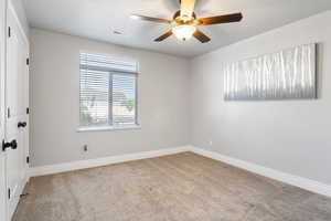 Empty room featuring ceiling fan and light carpet