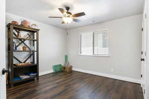 Empty room featuring ceiling fan and dark hardwood / wood-style floors