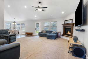 Living room with ceiling fan, lofted ceiling, plenty of natural light, and wood-type flooring