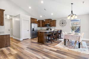 Kitchen with appliances with stainless steel finishes, hardwood / wood-style floors, an inviting chandelier, and light stone countertops