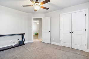 Interior space featuring a closet, ceiling fan, and light colored carpet