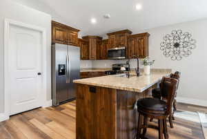 Kitchen with light wood-type flooring, vaulted ceiling, kitchen peninsula, and appliances with stainless steel finishes