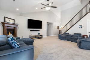 Living room featuring high vaulted ceiling, ceiling fan, and carpet flooring