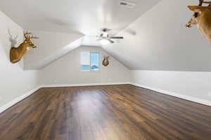 Additional living space featuring a textured ceiling, vaulted ceiling, dark hardwood / wood-style flooring, and ceiling fan