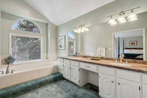 Primary Suite Bathroom featuring Granite Vanity, lofted ceiling, large tub, and a healthy amount of sunlight