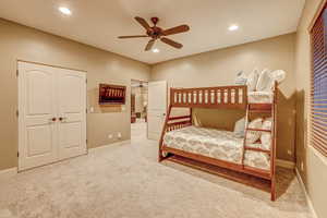 Carpeted bedroom featuring ceiling fan and a closet