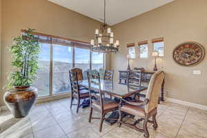 Tiled dining space with a chandelier and high vaulted ceiling