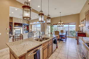 Kitchen with dishwasher, a center island with sink, plenty of natural light, and hanging light fixtures