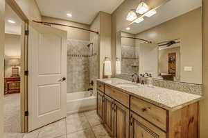 Bathroom featuring tile patterned floors, ceiling fan, tiled shower / bath combo, and vanity