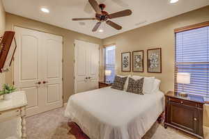 Carpeted bedroom with two closets and ceiling fan