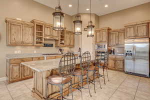 Kitchen with light tile patterned floors, a kitchen island, pendant lighting, and stainless steel appliances