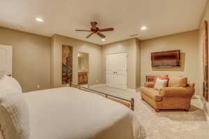 Carpeted bedroom featuring a closet, ceiling fan, and ensuite bathroom