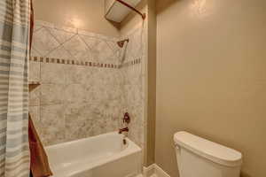 Bathroom with shower / bath combo with shower curtain and toilet